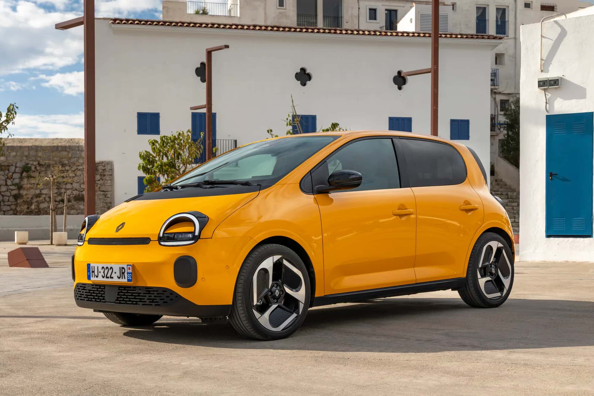 Renault Twingo E-Tech Techno 2026 en jaune Mango, statique trois quarts avant en centre-ville d'Ibiza, jantes 18 pouces visibles