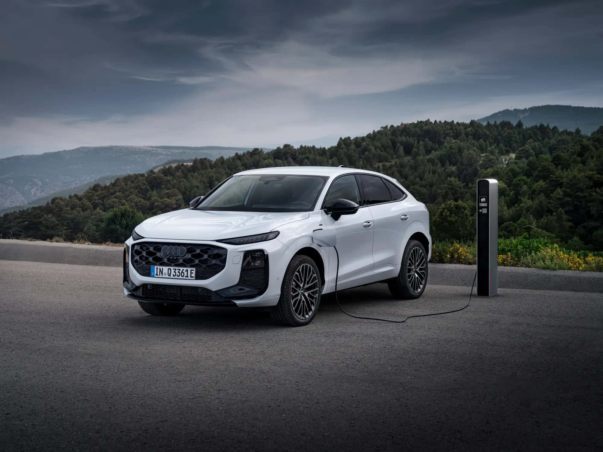 L'Audi Q3 Sportback e-hybrid blanche branchée à une borne de recharge, vue de trois quarts avant