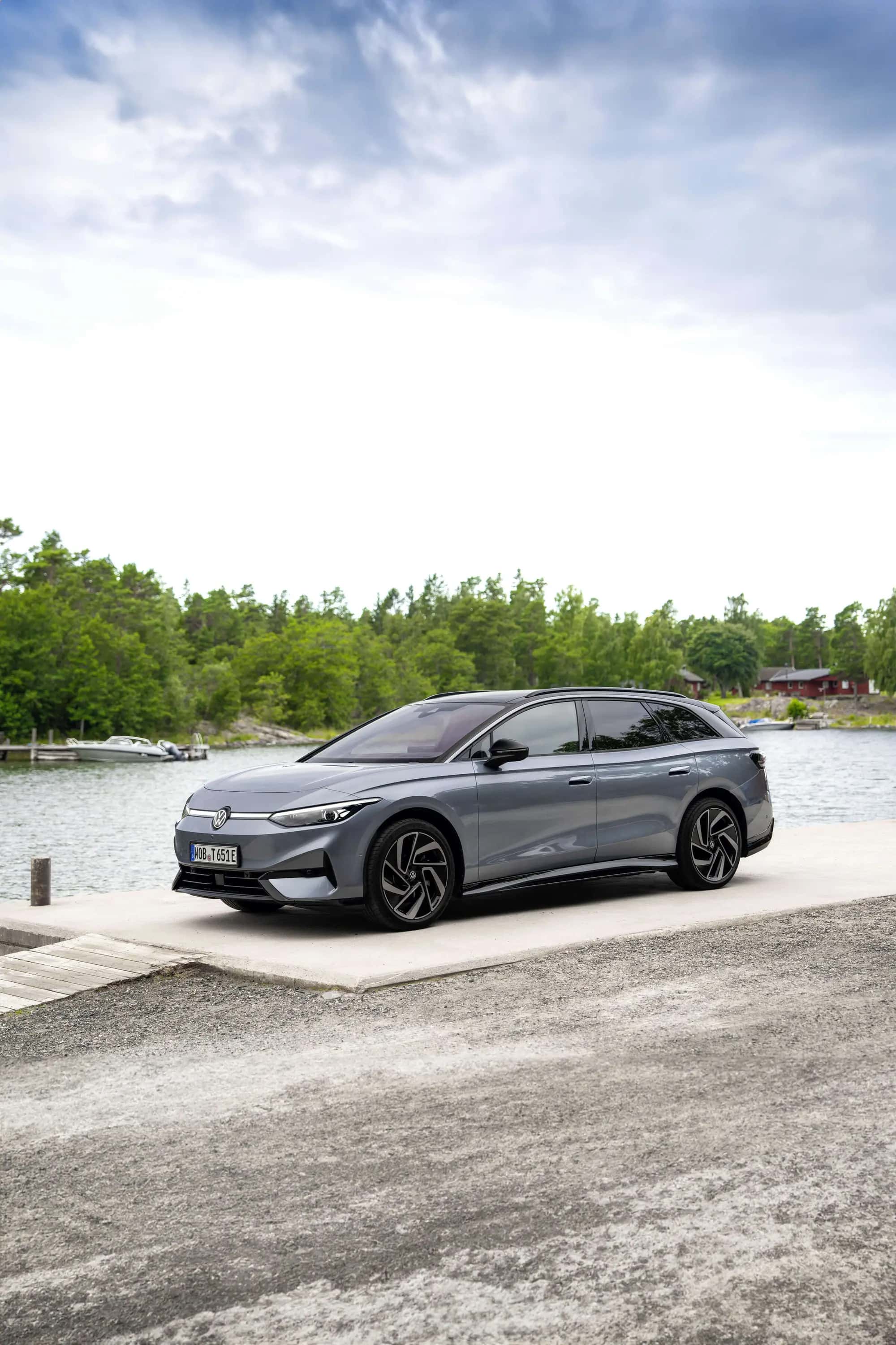Le break Volkswagen ID.7 Tourer gris vu de trois quarts avant, au bord de l'eau