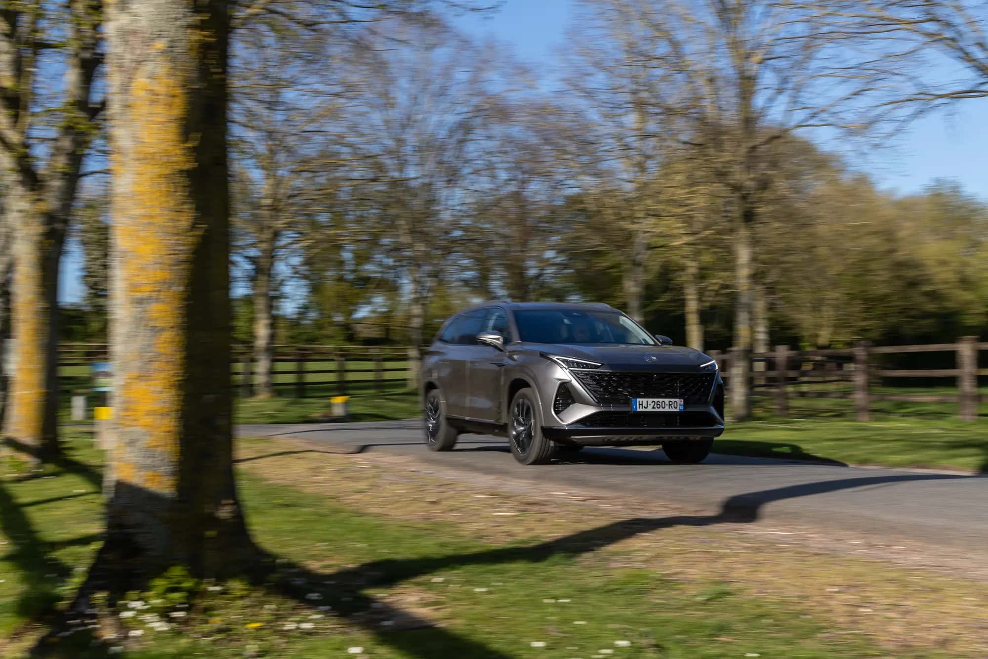 Le SUV MG S9 PHEV gris foncé vu de trois quarts avant sur une route de campagne