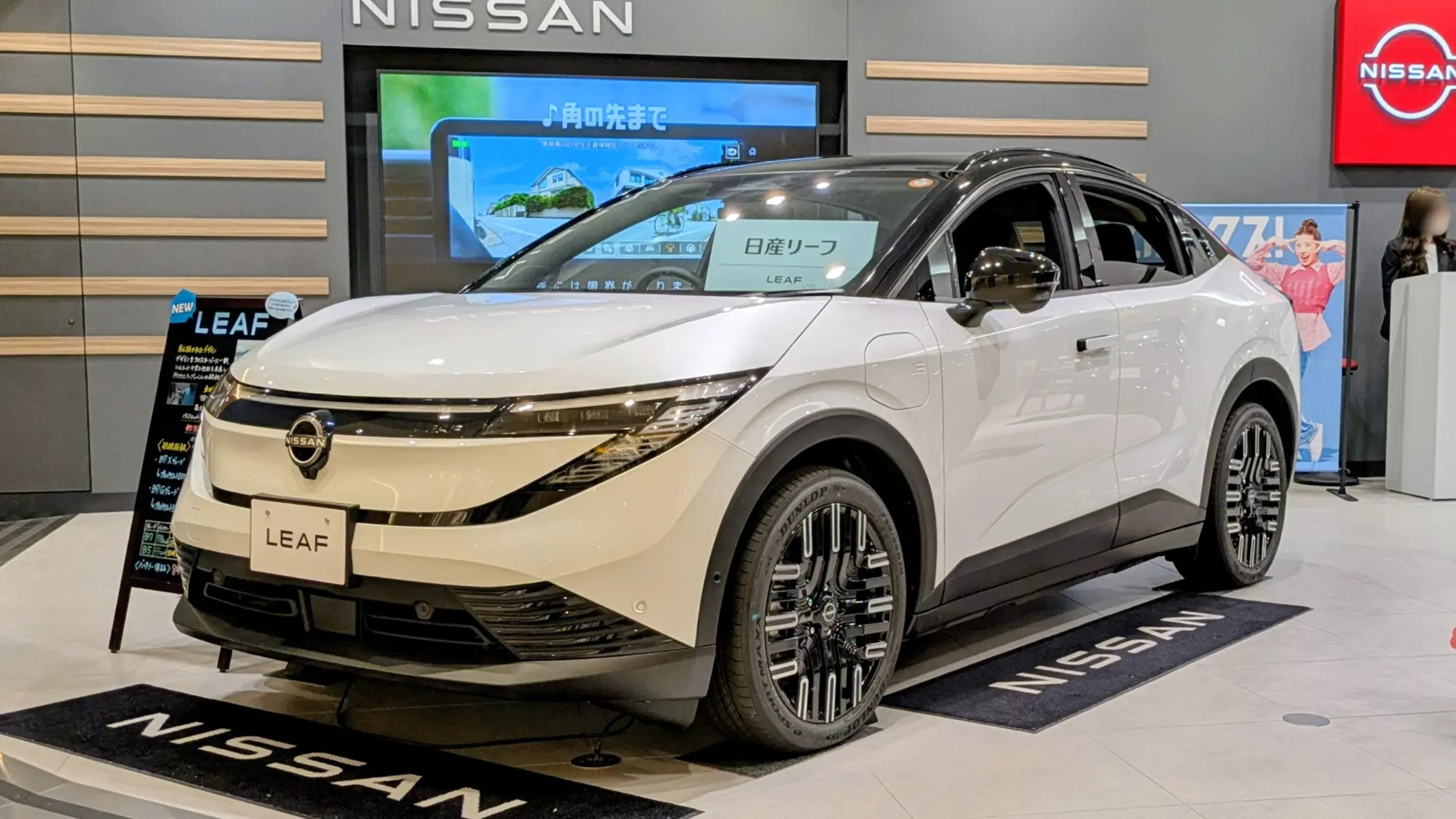La Nissan Leaf 2026 blanche vue de trois quarts avant dans un espace d'exposition