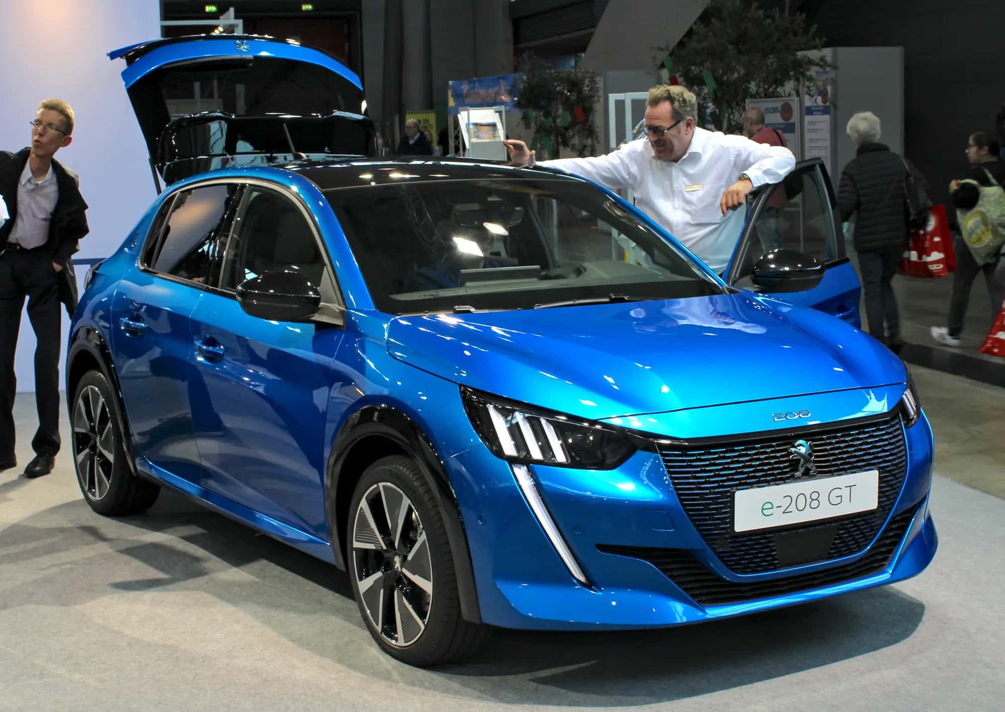 La Peugeot e-208 bleue exposée sur un stand, vue de trois quarts avant