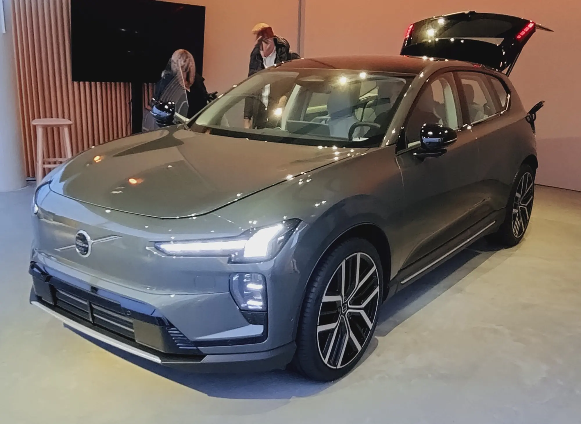 Le Volvo EX60 gris vu de trois quarts avant sur un stand d'exposition
