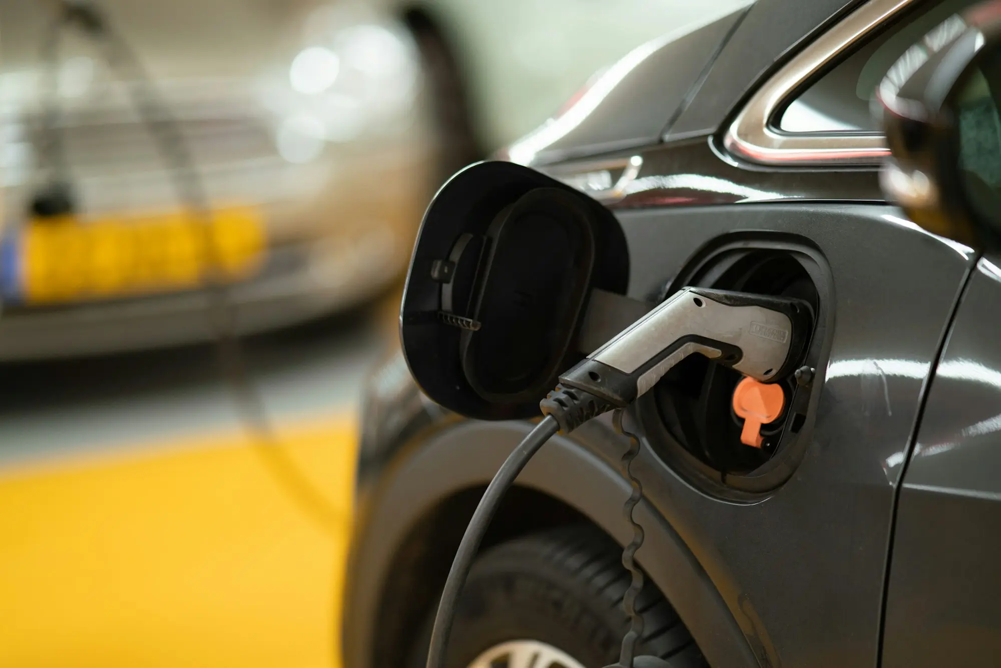 Gros plan sur un connecteur de recharge branché à la trappe d'une voiture électrique