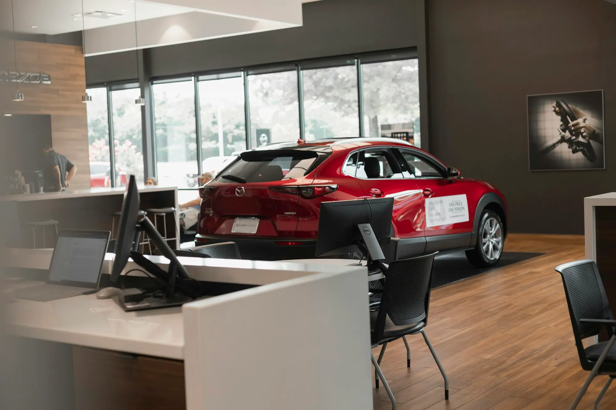 Une voiture rouge exposée dans le hall vitré d'une concession automobile