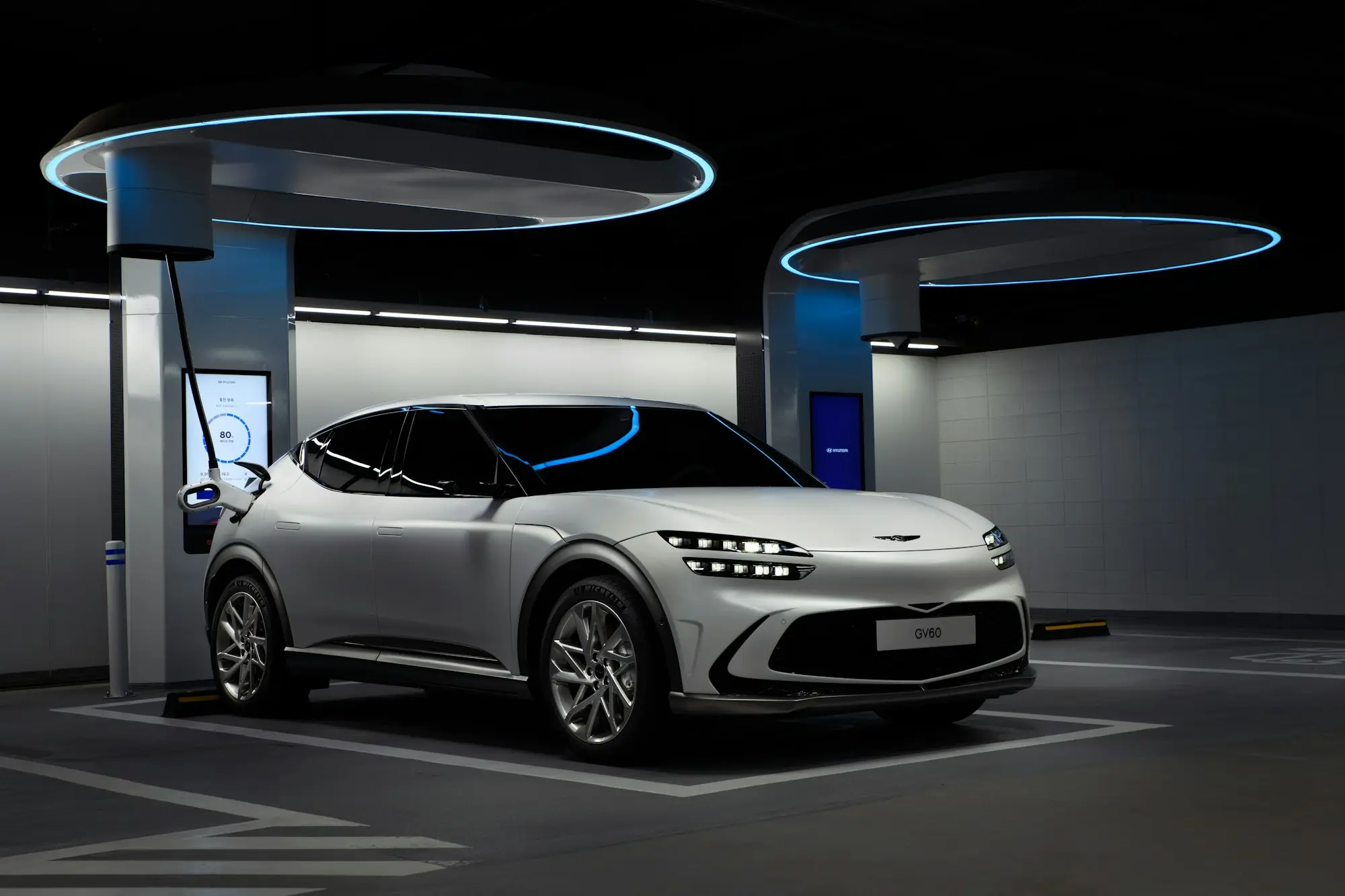 Une voiture électrique branchée sous les arches lumineuses d'une station de recharge