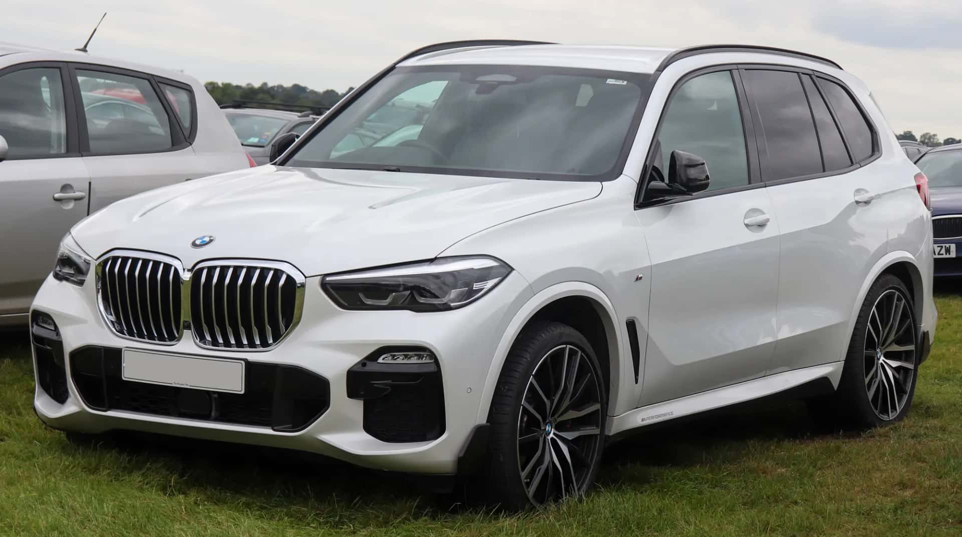 Un grand SUV blanc garé sur l'herbe, vu de trois quarts avant