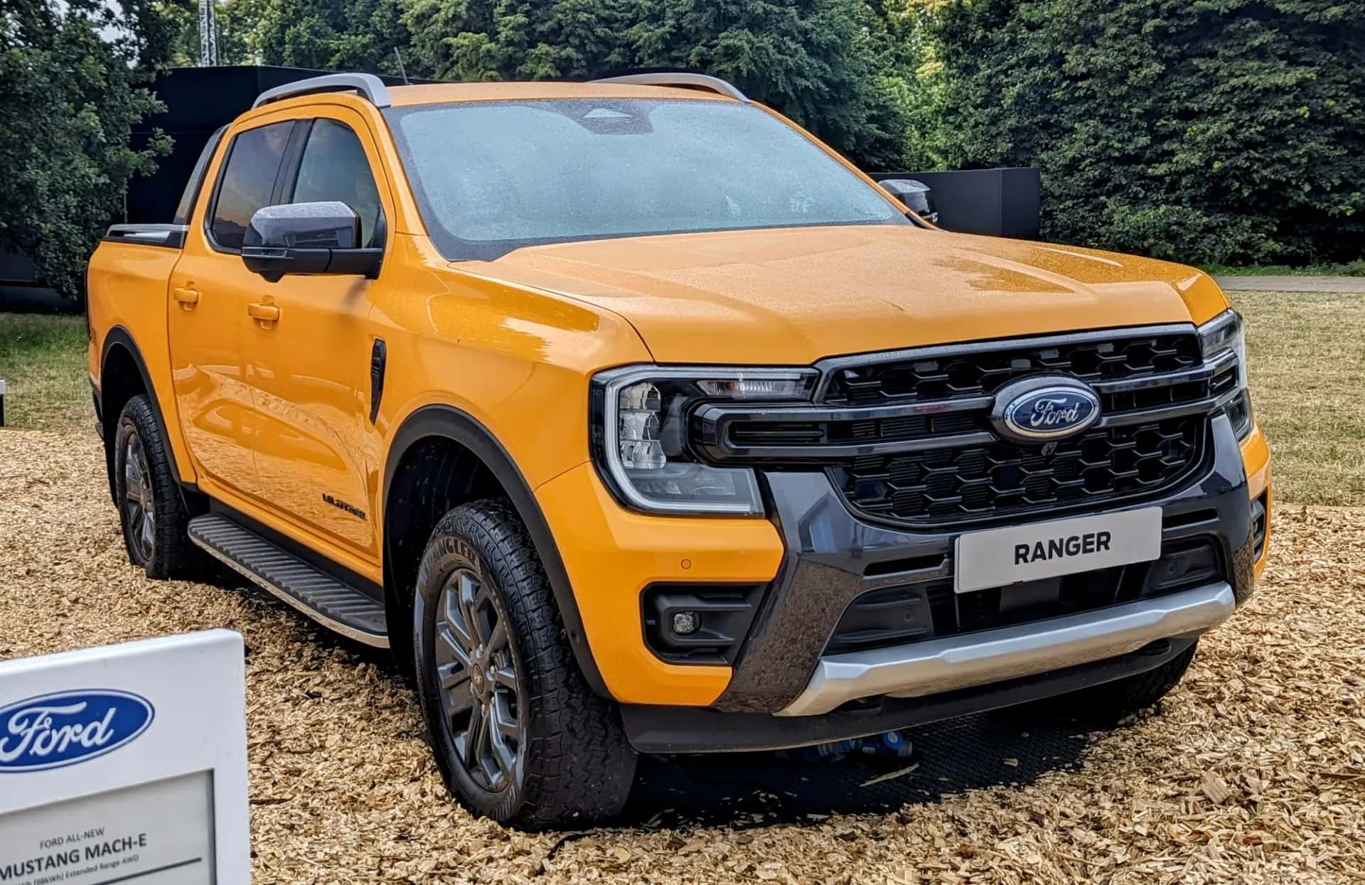 Pick-up Ford Ranger Wildtrak double cabine orange vu de trois quarts avant, garé sur des copeaux de bois