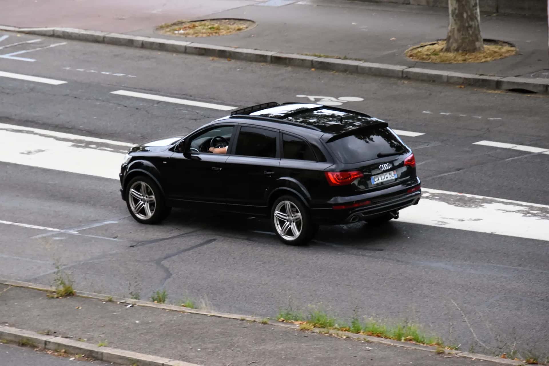 Un grand SUV noir circulant sur une avenue, vu de trois quarts arrière