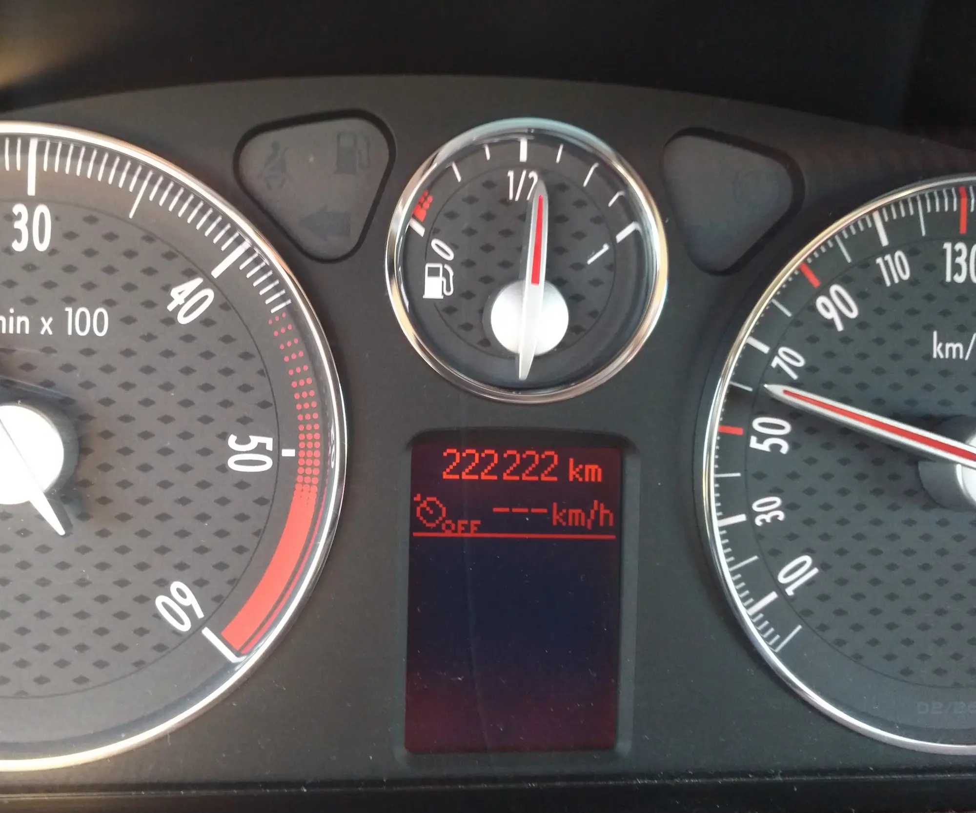 Le tableau de bord d'une voiture affichant un compteur à 222 222 kilomètres