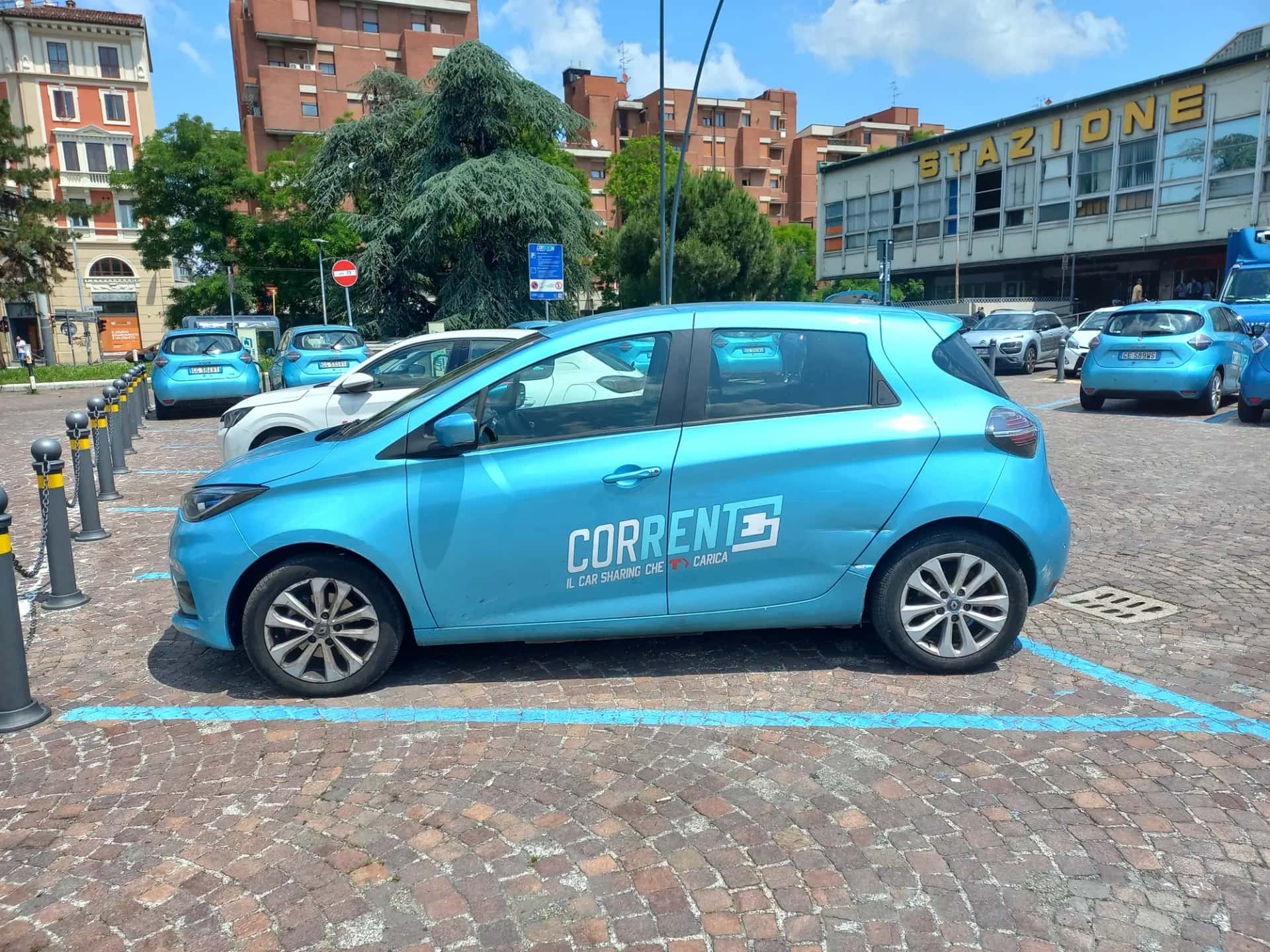 Une file de citadines électriques bleues identiques garées sur des places de recharge