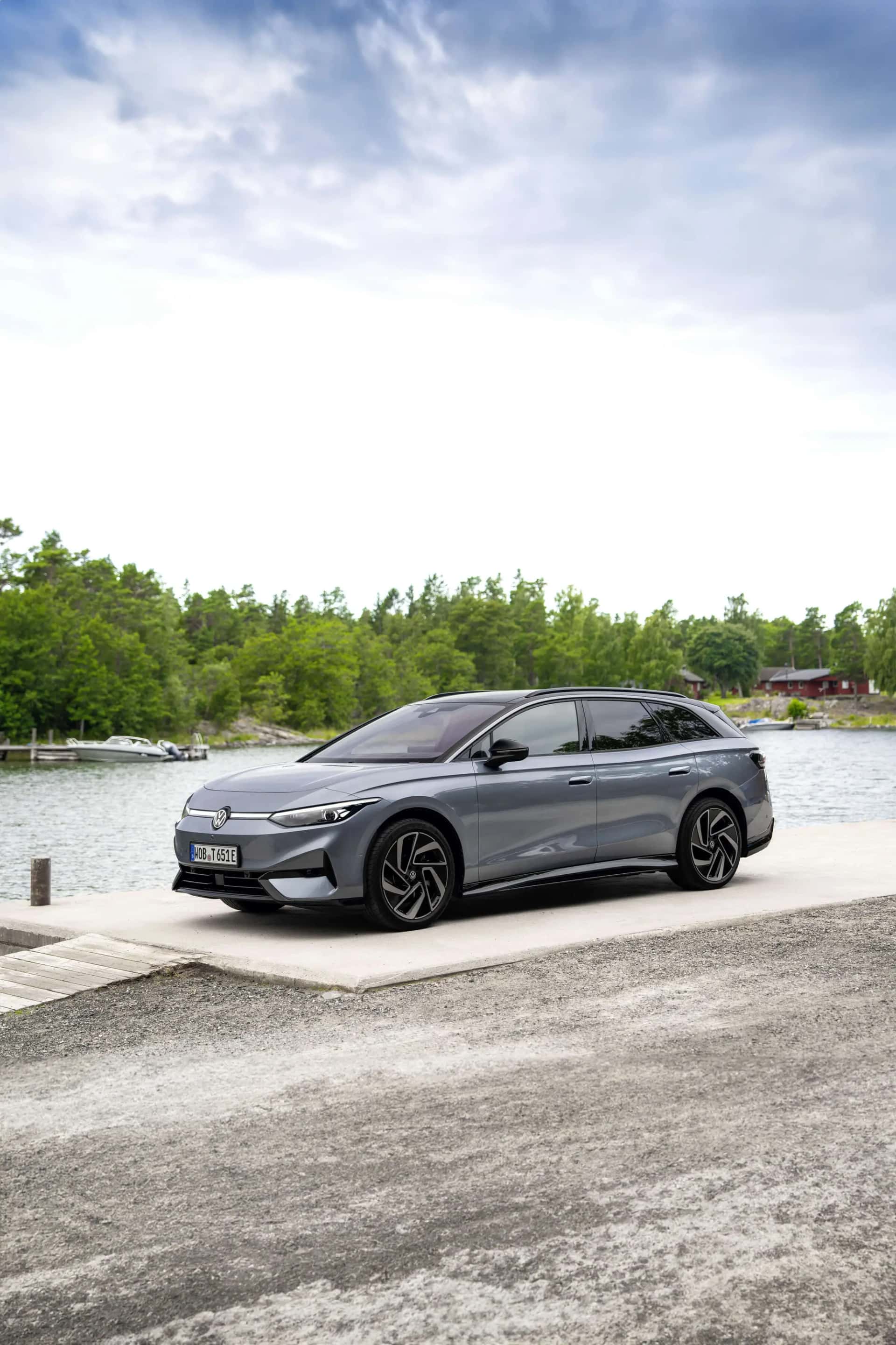 Le break Volkswagen ID.7 Tourer gris vu de trois quarts avant, au bord de l'eau