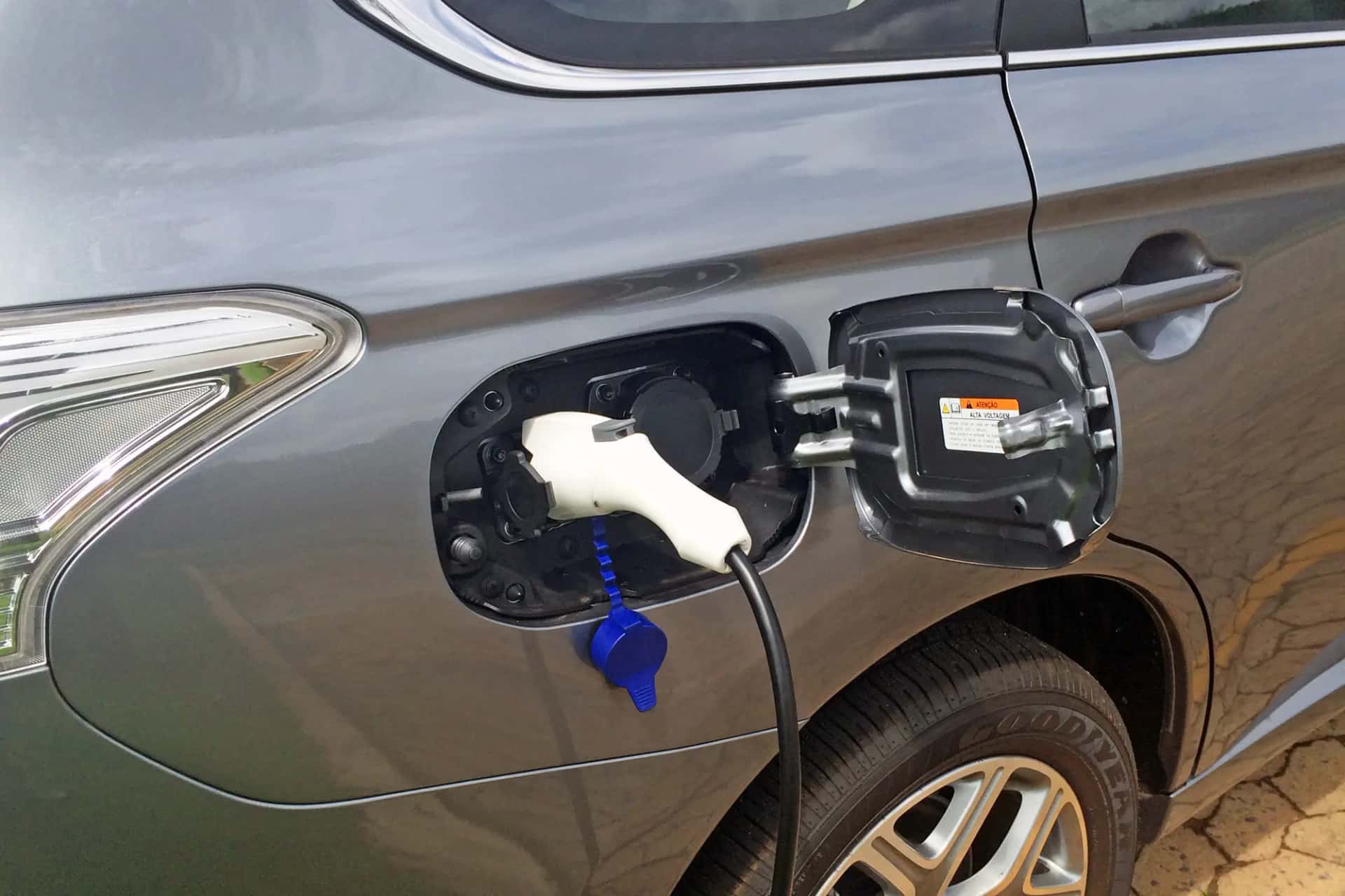 Gros plan sur la trappe de charge ouverte d'un SUV hybride, câble branché