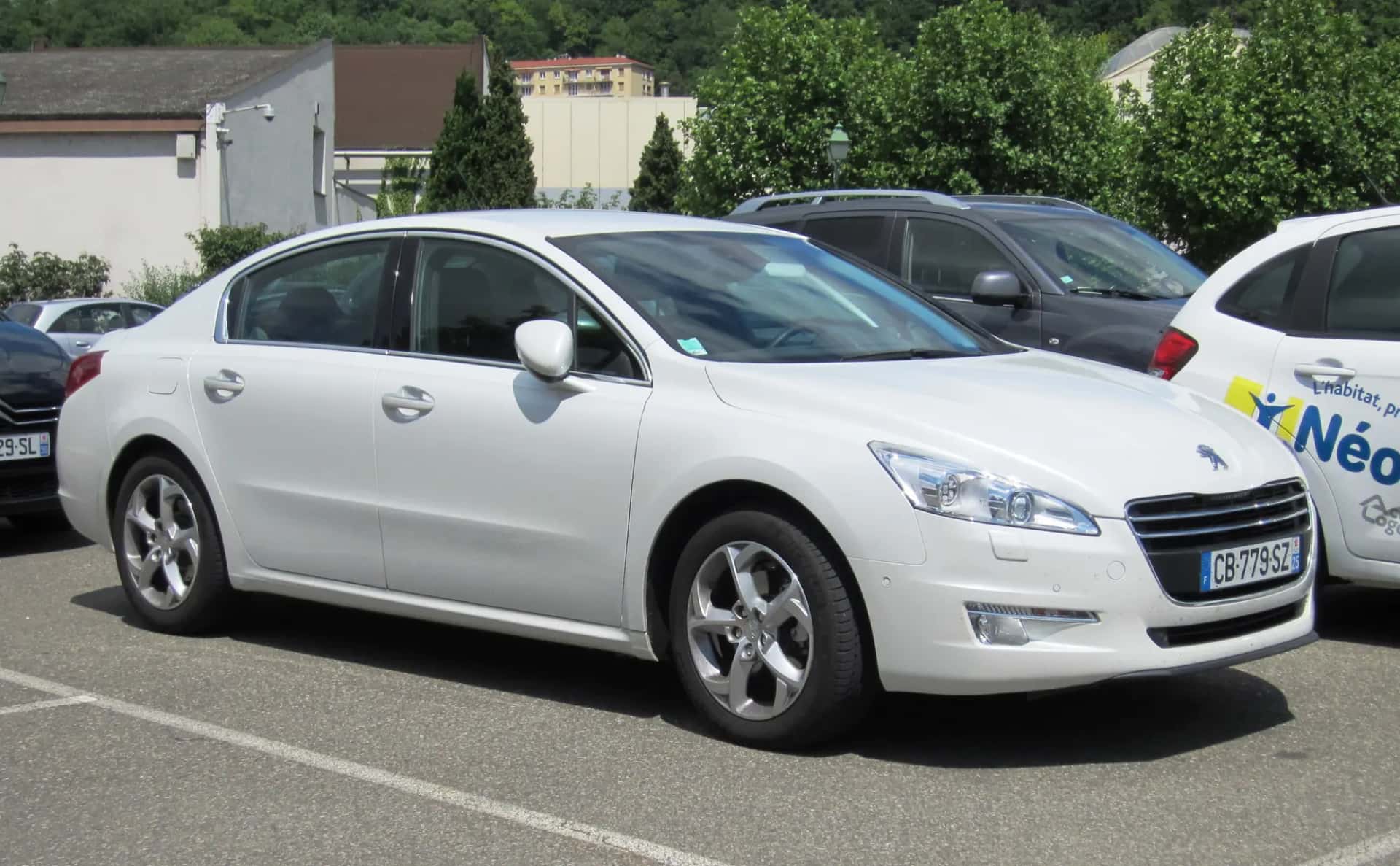 Une berline blanche garée sur un parking d'entreprise, vue de trois quarts avant