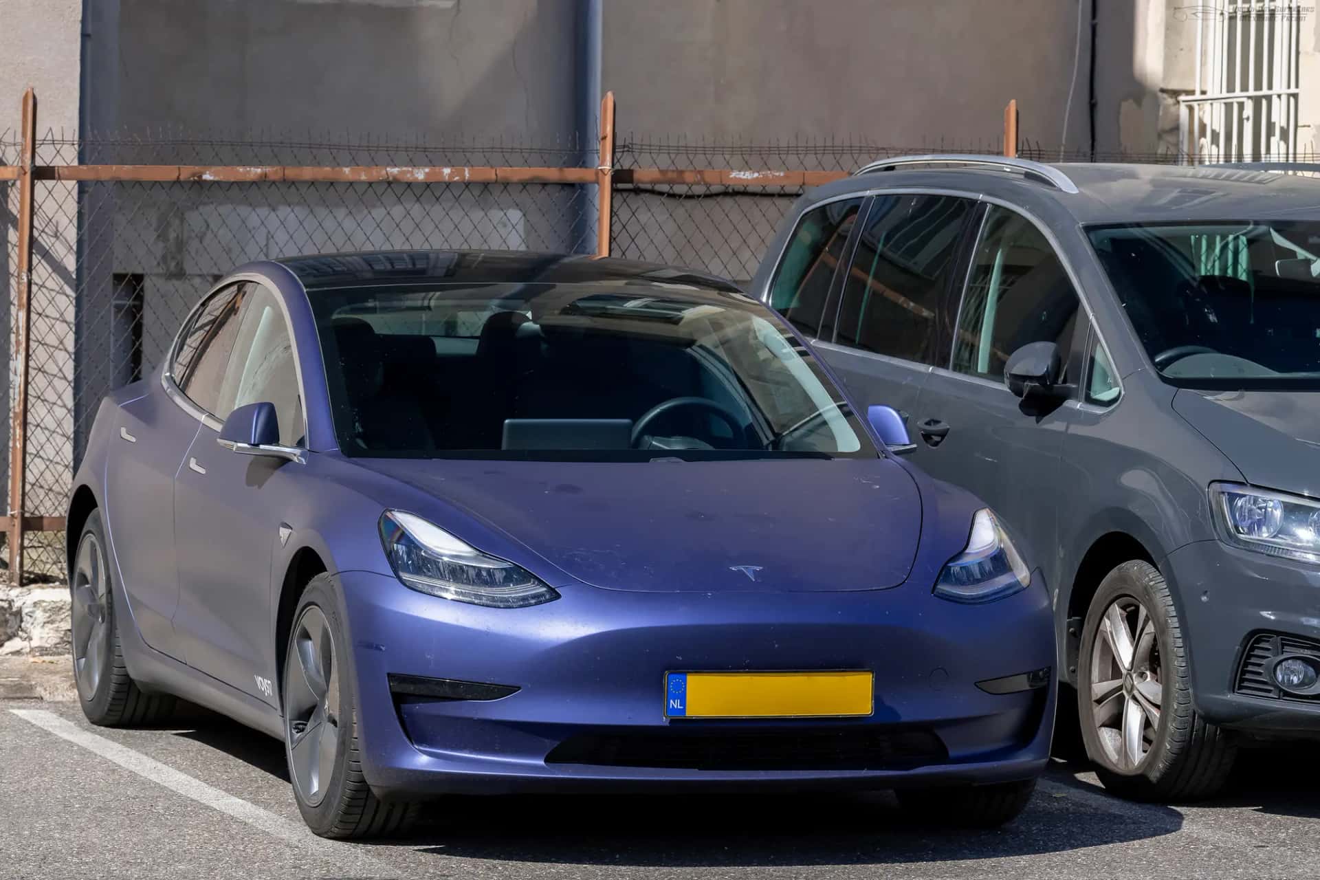 Deux véhicules électriques garés côte à côte sur un parking, dont une berline bleue