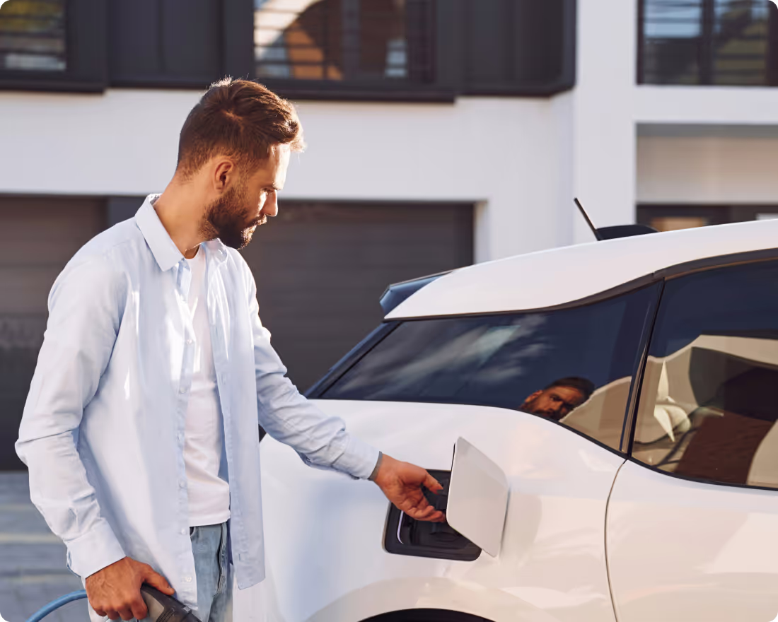 Un collaborateur branche le câble de recharge de sa voiture électrique devant son garage